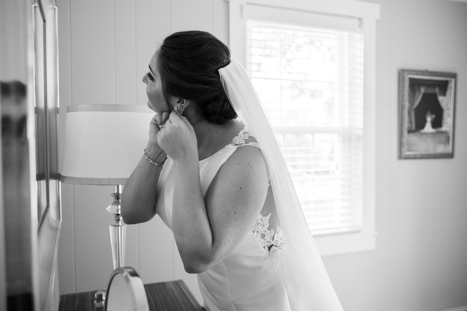 Bride putting in earrings in front of mirror in the bridal suite for a Rockfield Manor Wedding
