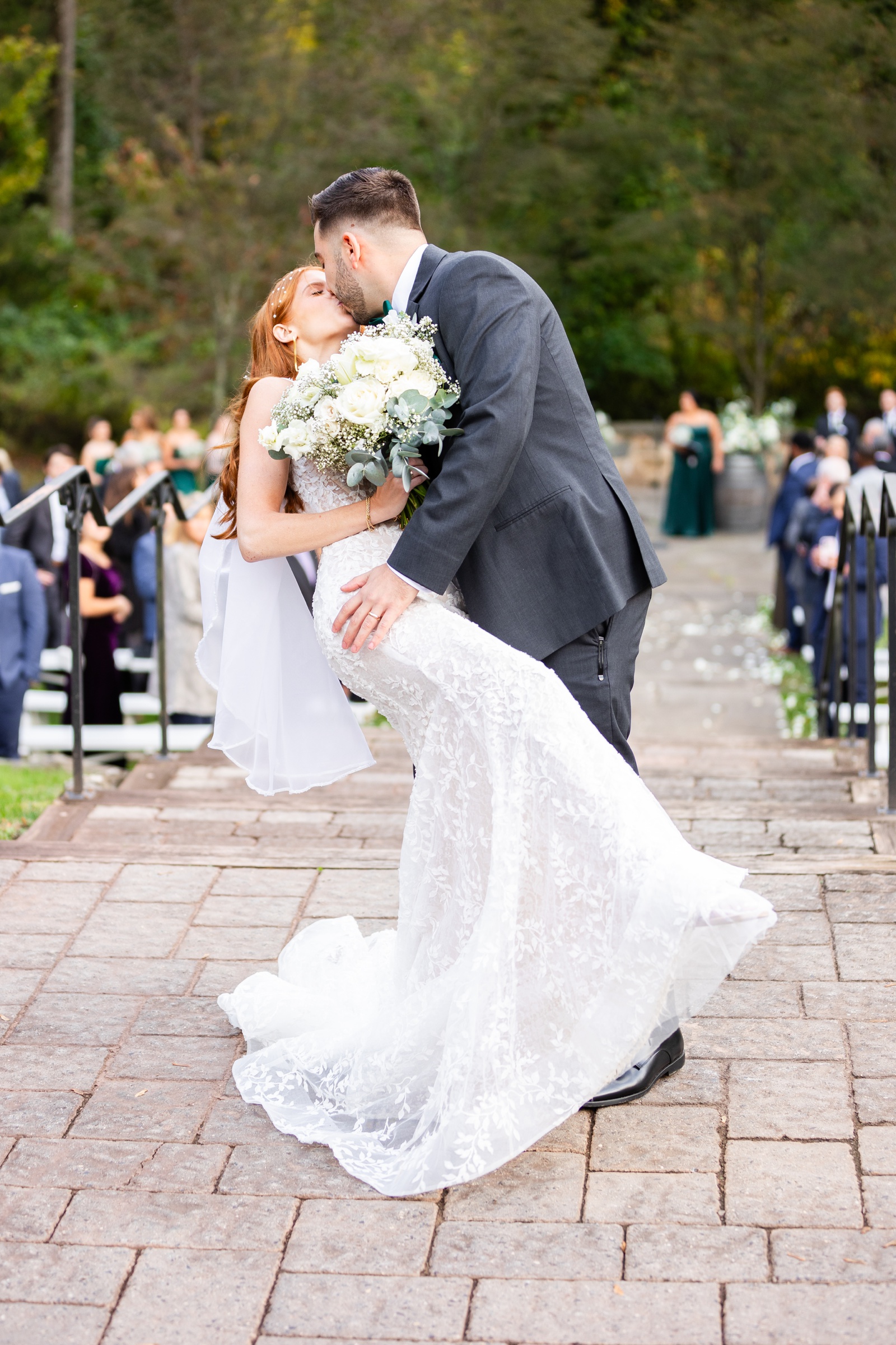 Outdoor wedding ceremony at The Inn at Grace Winery, with the groom dipping his bride at the end of the wedding aisle