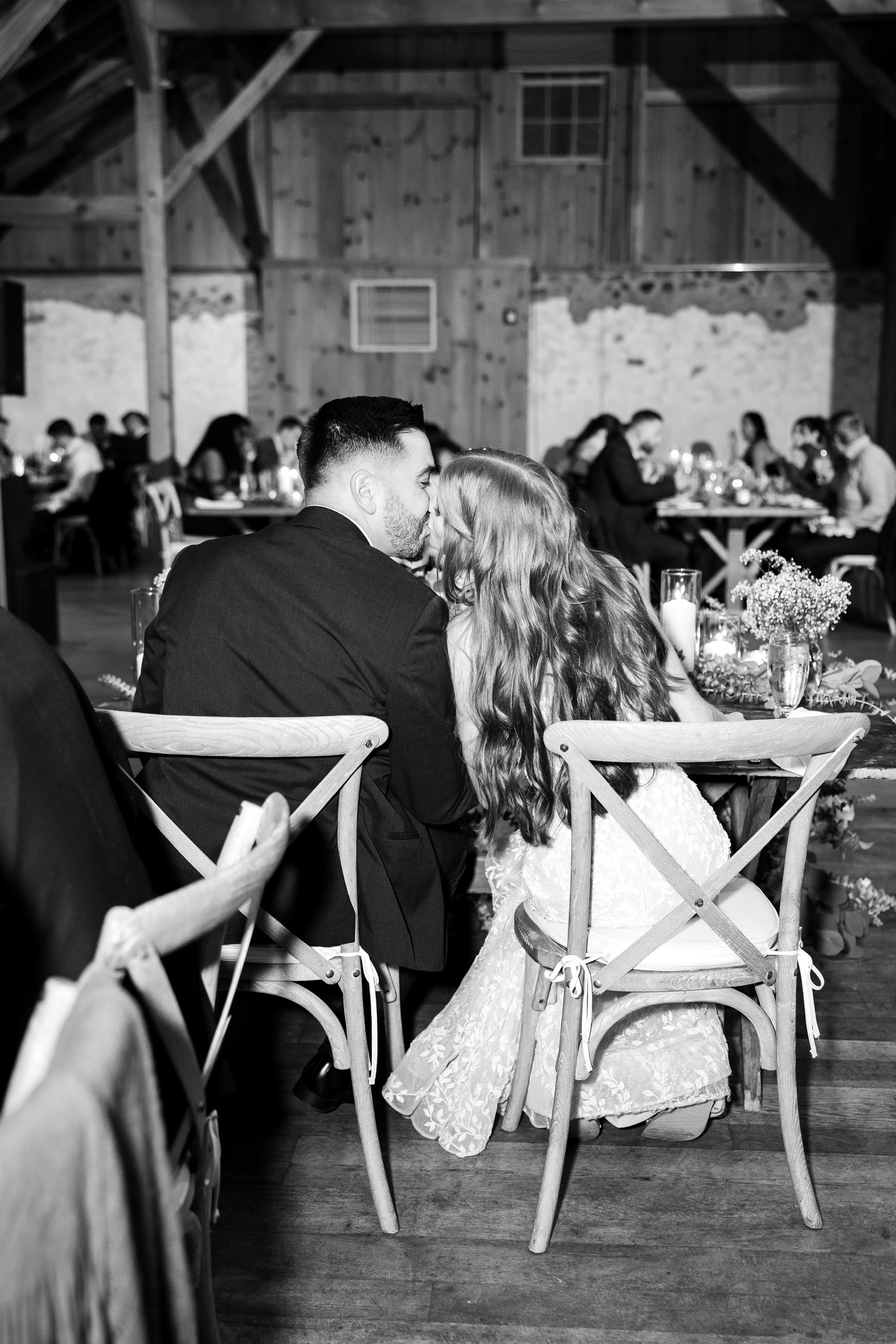 Bride and groom kissing at their sweetheart table, surrounded by family and friends at a wedding reception in Pennsylvania 