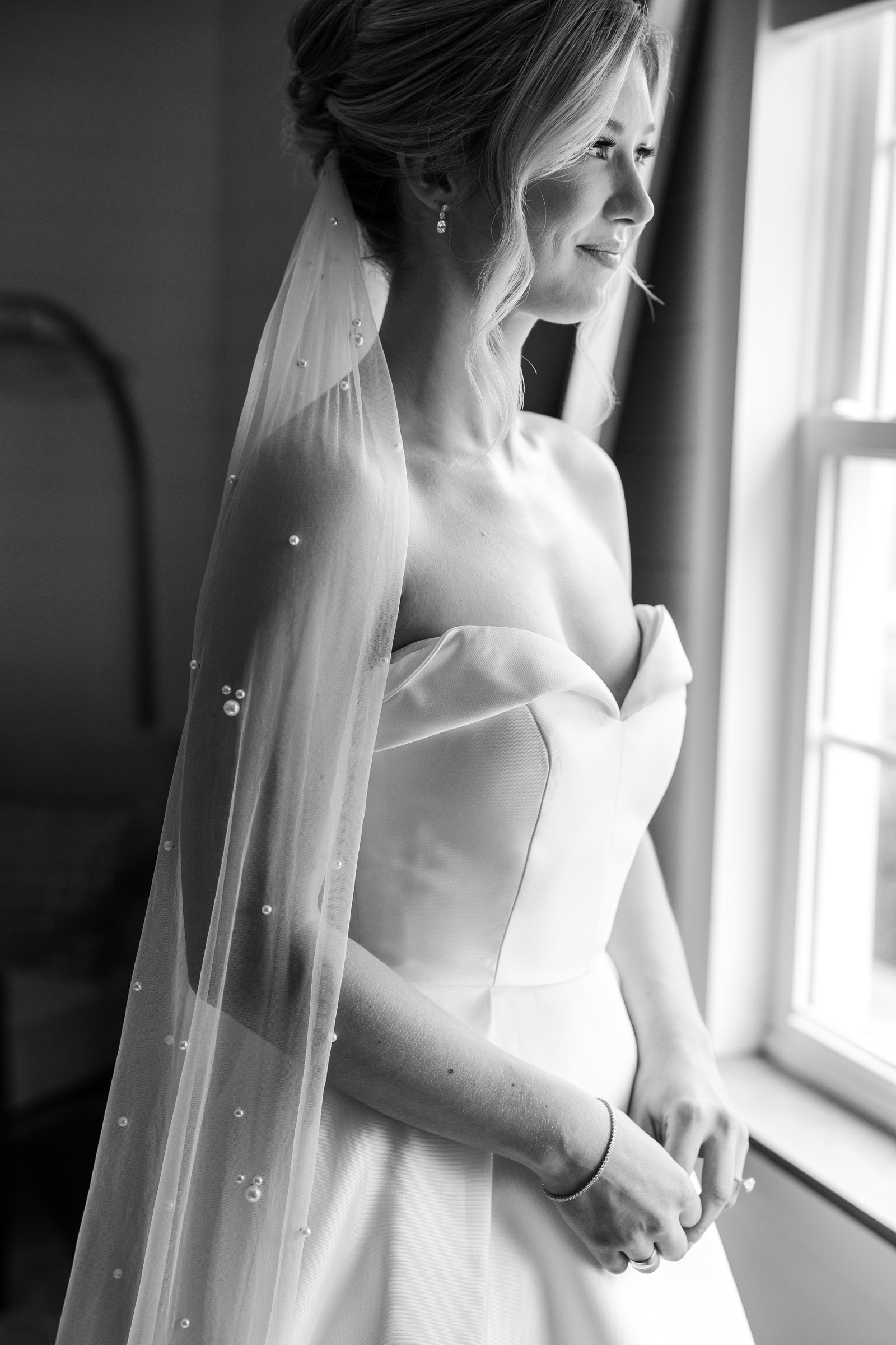 Bride getting ready for her wedding at Kent Island Resort, wearing a satin strapless down with pearl covered veil.