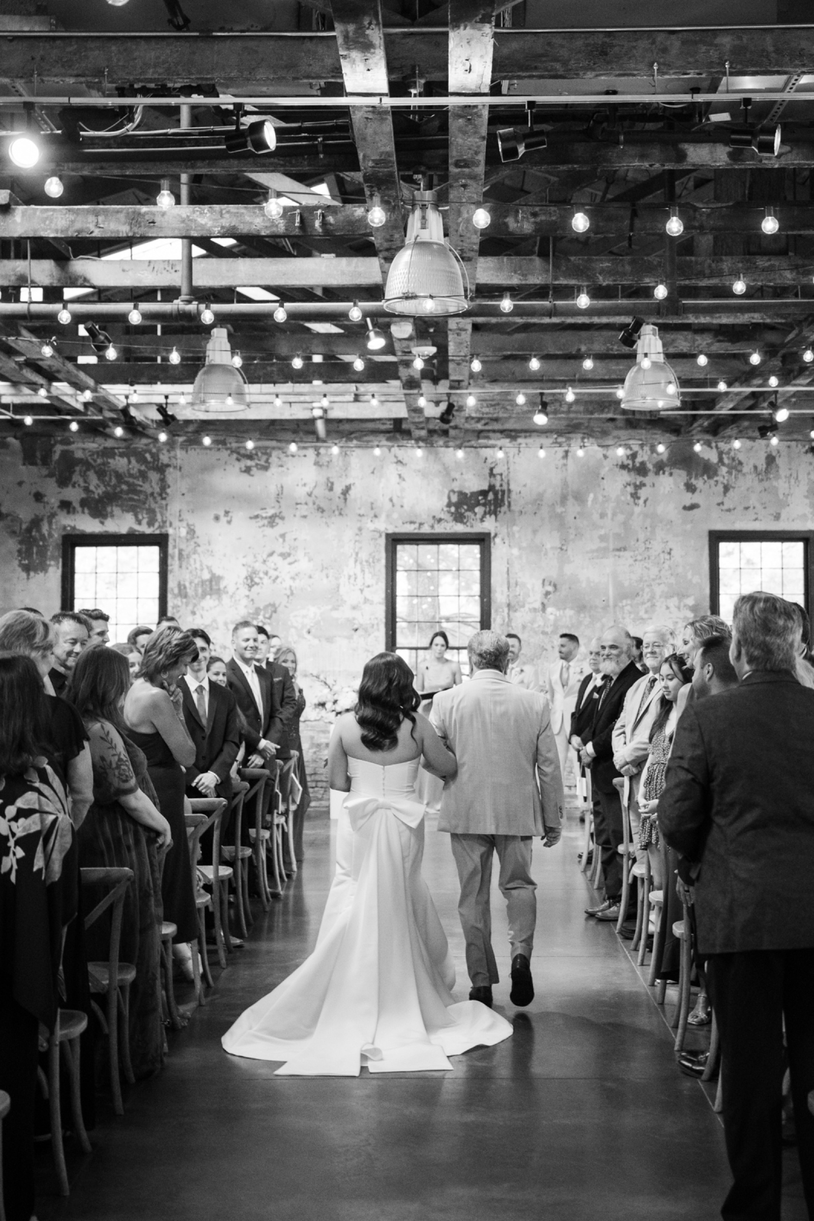 Black and white image of a bride walking down the aisle with her dad, at her wedding ceremony at Mt. Washington Mill Dye House