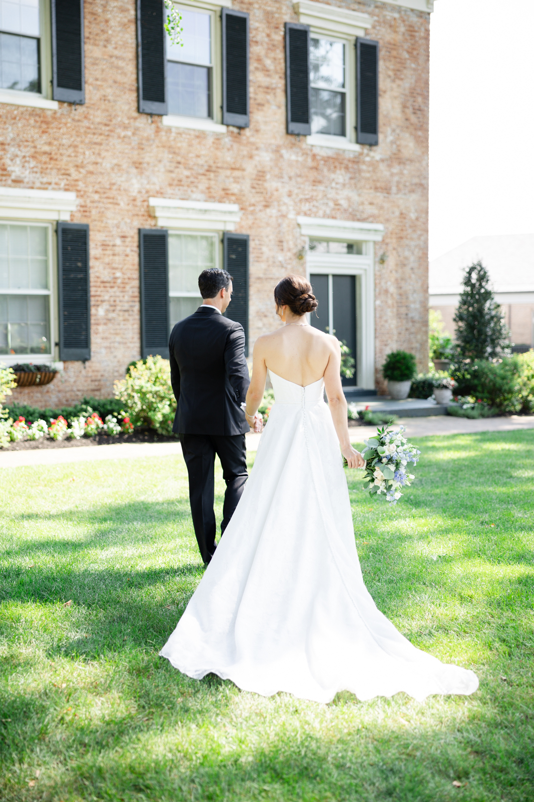 Bride and groom walking hand in hand on the lawn at their Woodmont Country Club wedding in Rockville, Maryland